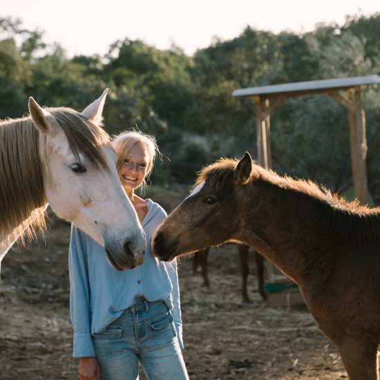 Frau mit Pferd und Fohlen im Abendlicht im Alentejo. Sinnbild für pferdegestützte Therapie in Portugal