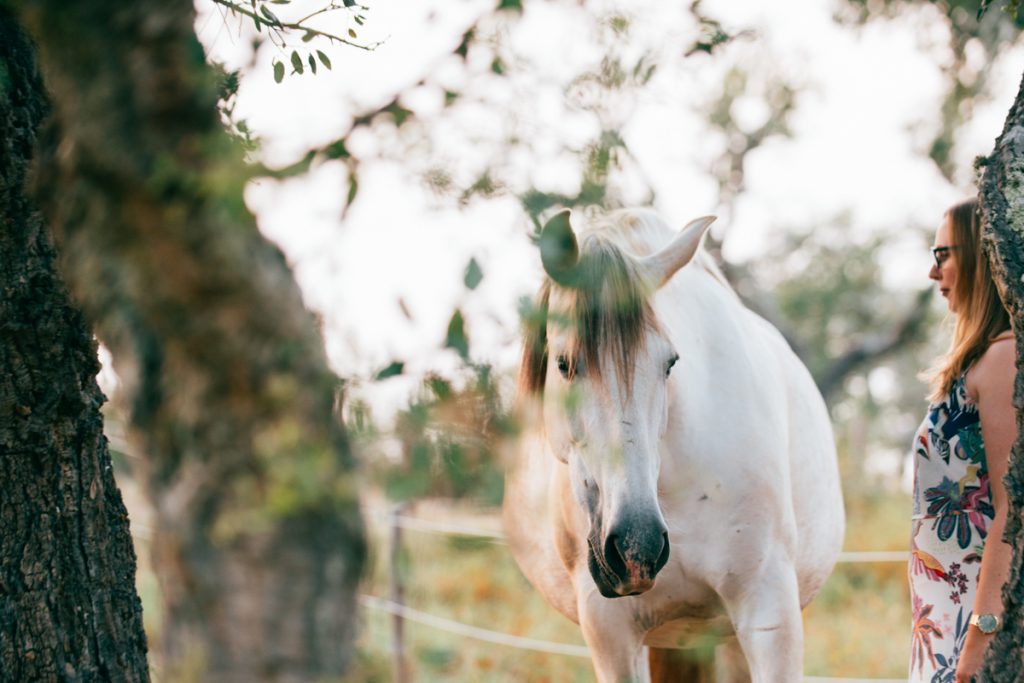 Frau mit geschlossenen Augen neben weißem Pferd bei einem Frauenretreat in Portugal